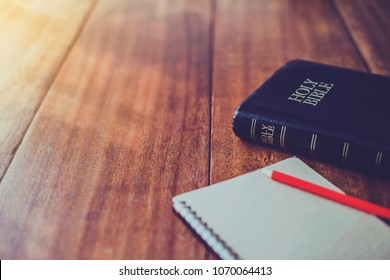 Библия с записной книжкой и карандашом на деревянном столе против утреннего солнечного света для христианской преданности, место для копирования