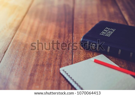 Holy bible with note book and pencil on wooden table against morning  sun light for christian devotion, copy space