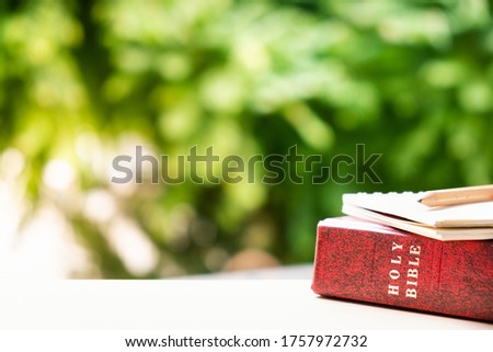 Holy Bible, notebook, and pencil with natural background