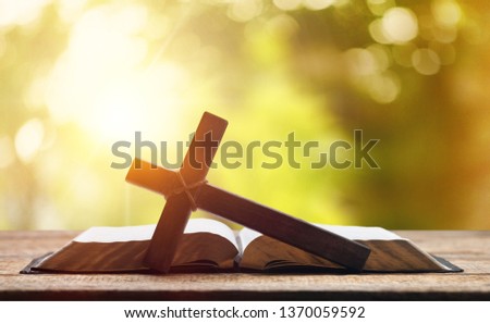 Holy Bible on the background of the Christian cross and the life-giving divine light. The hope of mankind for salvation. The way to God through prayer. The Resurrection and Rapture of Jesus.