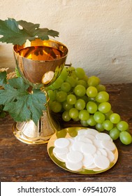 Holy communion image showing a golden chalice with grapes and bread wafers
