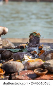 holy god shivalinga worshiped by devotee with flowers at river shore at morning