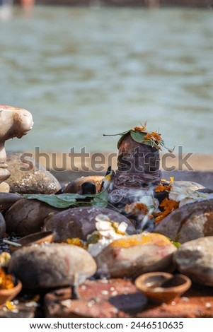 holy god shivalinga worshiped by devotee with flowers at river shore at morning