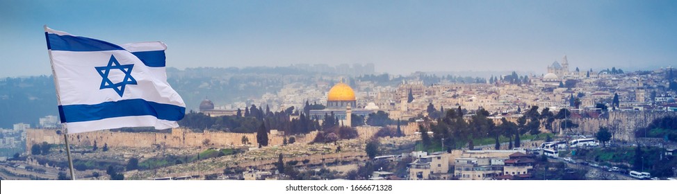 The Holy Land Of Jerusalem With Flag Of Israel Over The Old City In Haze. Cityscape Of Jerusalem Walls On The Way Of Pilgrims And Sacred Place Of Three World Religions - Christians, Muslims And Jews.