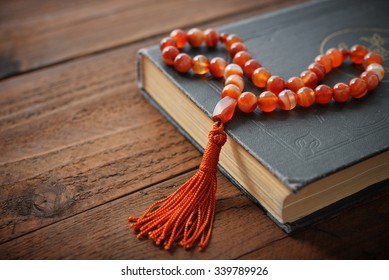 Holy Quran with beads over wooden background close up