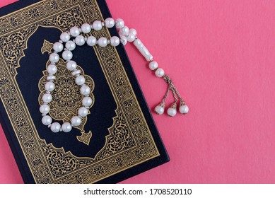 The Holy Quran With Rosary Beads Isolated On Pink Background. Islamic And Ramadan Concept.