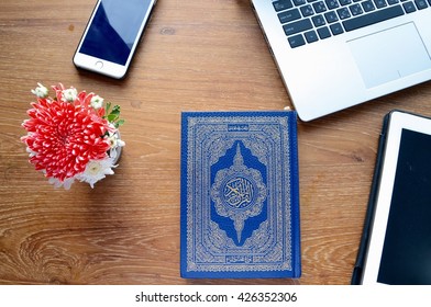 The Holy Quran(Islamic Book) on wooden table, on the cover is an Arabic text:An English translation is the name of the book, The Holy Quran