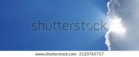 Holy spirit long banner. Blue sky with the rays of the sun coming out of a white cloud. Religious background with sky and sunbeams. Sunny clear weather background for weather forecast and meteorology.