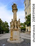 Holy Trinity Statue in front of the Mary Magdalene church in Zalaegerszeg on a sunny day.