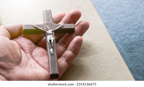 Holy wooden cross held on a hand with yellow texture in background                              - Shutterstock ID 2314136675