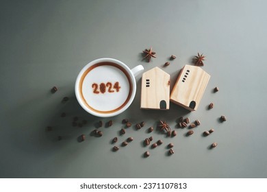 Home 2024 theme white coffee cup with number 2024 over frothy surface flat lay on grey background with wooden house model, coffee beans and star anise. New year's resolutions for family. (top view) - Powered by Shutterstock