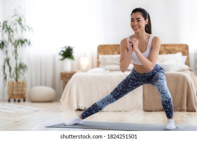 Home Aerobics. Happy Sporty Asian Woman Doing Lunges Exercises On Mat In Bedroom, Enjoying Domestic Fitness Training And Healthy Lifestyle, Dressed In Stylish Sportswear And Smiling, Copy Space