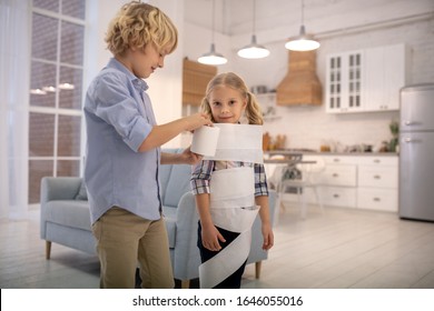 Home Alone. Two Kids Playing Toilet Paper Mummy Game At Home And Looking Entertained