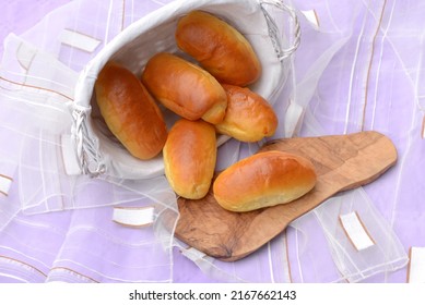 Home baked burger buns, small breads with shiny crust in white breadbasket and on wooden board. Delicious sandwich breads. Fresh baked bread rolls with soft crust and fluffy crumb. 