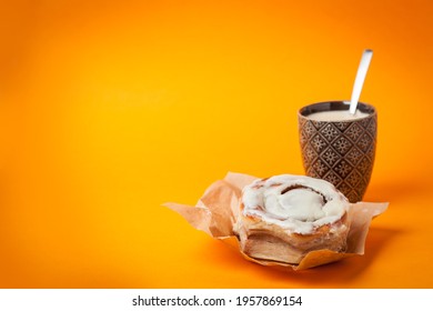 Home Baked Cinnamon Roll And Coffee On Orange Background