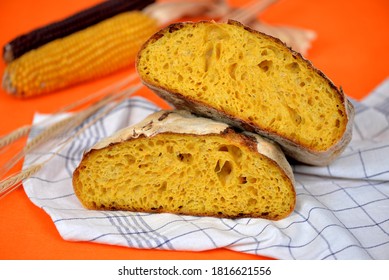 Home Baked Pumpkin Bread With Wheat And Corn Flour On Dish Cloth; Bread Texture Of Pumpkin Bread Loaf Cut In Half; Corn Cobs And Wheat Ears In Background 