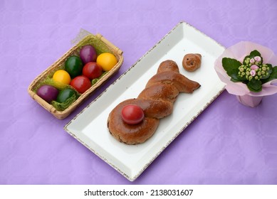 Home Baked Sweet Bread Bunny Holding Red Coloured Egg. Easter Cake With Walnut Stuffing In A Shape Of Easter Rabbit With Easter Eggs. Chocolate Roll Stuffed With Walnuts And Braided In Bunny Shape.