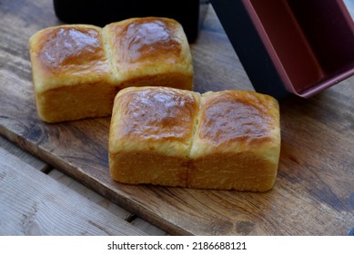 Home Baked Sweet Bread Rolls On Wooden Board. Bread Texture Of Sweet Buns For Sweet Sandwich With Baking Pans In Background. Delicious Small Breads With Shiny Crust And Soft Crumb.