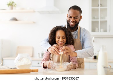 Panadería. Emocionado hombre afroamericano que agrega huevo a la masa de galletas, alegre hija que lo observa, aprendiendo a cocinar junto con papá, haciendo pastel el día del padre, copiando espacio