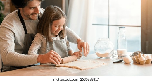 Home bakery. Loving dad showing to his little daughter how to roll the dough while preparing pastry in kitchen together, free space - Powered by Shutterstock