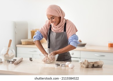Home Bakery. Portrait Of Beautiful Muslim Lady In Hijab Baking In Kitchen, Happy Smiling Islamic Woman Wearing Apron Kneading Dough For Cookies, Enjoying Cooking Homemade Pastry, Copy Space