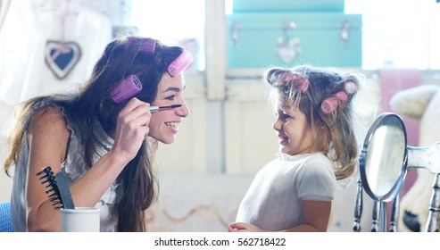 At Home, In The Bedroom, Mother And Daughter Play To Put On Makeup, Combing Hair Together. The Mother And Daughter Smiling As They Try Beauty Tricks. Concept: Beauty, Family, Fun, Memories.