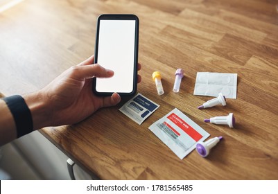 Home Blood Test Kit With Blank Phone Screen On Wooden Table In Mans Hands.