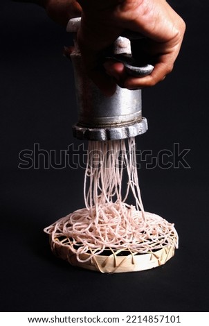 Home brew string hoppers. Lady making string hoppers using traditional equipment and flour. Lady hands and equipment in black background sri lanka.