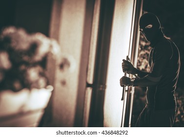 Home Burglar In A Mask Breaking Into The House. House Thief Concept Photo.