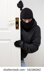 Home Burglary Concept With A Burglar Sneaking In A Open House Door