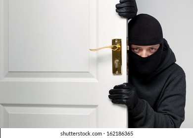 Home Burglary Concept With A Burglar Sneaking In A Open House Door