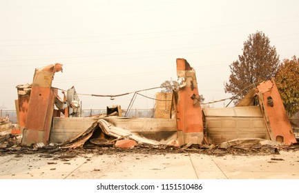 Home Burned To The Ground, Garage Door Buckled And Laying In A Heap After The Recent Wild Fire Fire Storm In Redding, CA. Smoke And Ash In The Air As The Fire Continues To Burn Several Miles Away.