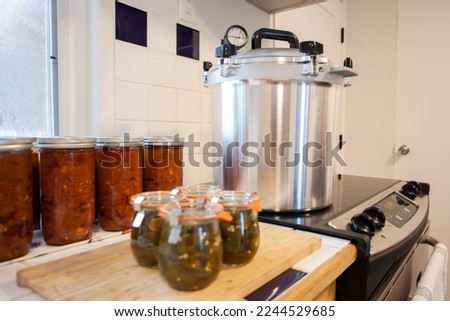 Home Canning jalapenos in jars and a batch of chili with a pressure cooker. Food preservation is key to gardening and homesteading. Pressure canning makes food shelf stable. 