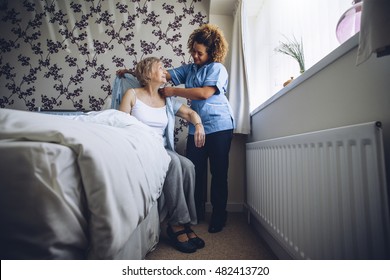 Home Caregiver helping a senior woman get dressed in her bedroom. 