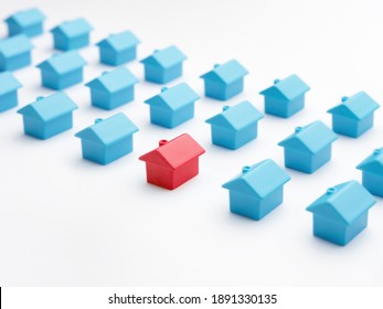 Home Choice Or Selection Property And Real Estate. Red House Model Among Blue Toy Houses On White Color Background. Unique House Different From Group Of Same Type Miniature Houses. Property Marketing