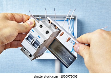 Home Circuit Breaker Setup.  Man Is Installation  A Single Pole 16 Amp Overcurrent Protection Device.  The Use Of A DIN Rail For Mounting The Breakers.