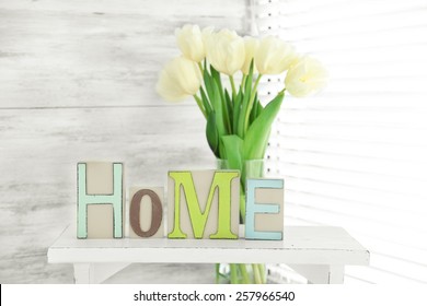 Home In Colorful Letters And Spring Flowers In Light White Interior