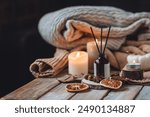 Home comfort, coziness, aromatherapy. Cozy interior with knitting, burning candles and aroma perfume diffuser in the living room. Fall scent, sweet pumpkin pie fragrance, dry leaves, autumn mood