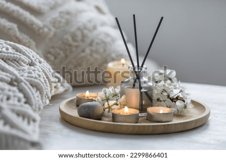 Home comfort, coziness, aromatherapy. Cozy interior with knitting, burning candles and aroma perfume diffuser in the living room. Fresh spring organic blossom fragrance, apple cherry flowers.