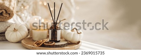Home comfort, coziness, aromatherapy. Cozy interior with knitting, burning candles and aroma perfume diffuser in living room. Pumpkin spicy sweet pie fall fragrance, autumn scent, relaxation banner