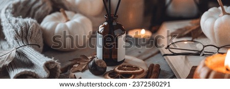 Home comfort, coziness, aromatherapy. Cozy fall interior with knitted wool warm sweater, burning candles and autumn aroma perfume diffuser. Pumpkin pie scent, maple sirup, cinnamon, anise. Banner