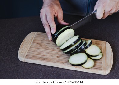 Home Cooking And Meal Prepping Concept, Man Cutting Aubergine Slices On Cutting Board