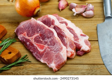 Home cooking. Pieces of fresh raw pork shoulder and condiments prepared for roasting on wooden table - Powered by Shutterstock