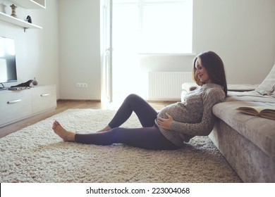 Home accogliente ritratto di donna incinta che riposa a casa e libro di lettura