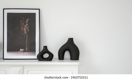 Home decor concept. Panoramic view of elegant black vase and mockup picture in frame on shelf above fireplace. New apartment with contemporary interior design and white copy space wall