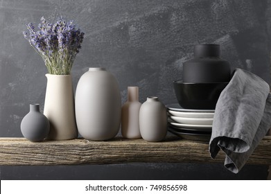 Home Decor - Neutral Colored Vases With Lavander Bouquet, Dishware And Linen Napkin On Rough Distressed Wooden Shelf Against Grey Wall.