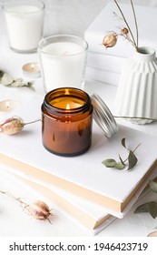 Home Decoration And Interior. Beautiful Burning Candles With Eucalyptus Leaves And Dry Flowers On Pile Of White Books