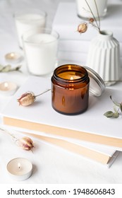 Home Decoration And Interior. Beautiful Burning Candles With Eucalyptus Leaves And Dry Flowers On Pile Of White Books