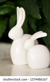 Home decoration of two ceramic Easter bunnies with green houseplants background