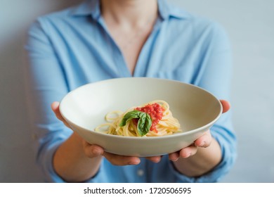 Home delivery food from the restaurant during a pandemic. Italian food delivery. Woman or chef holding plate with spaghetti